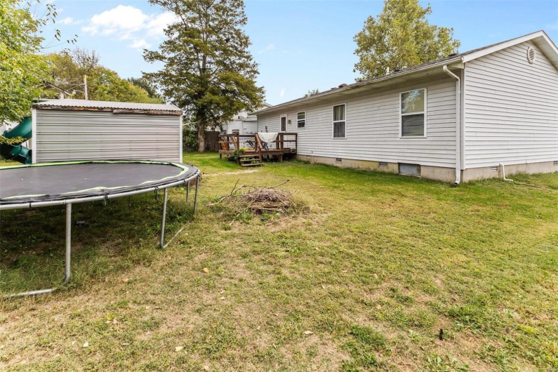 View of yard with a shed, a deck, and a trampoline