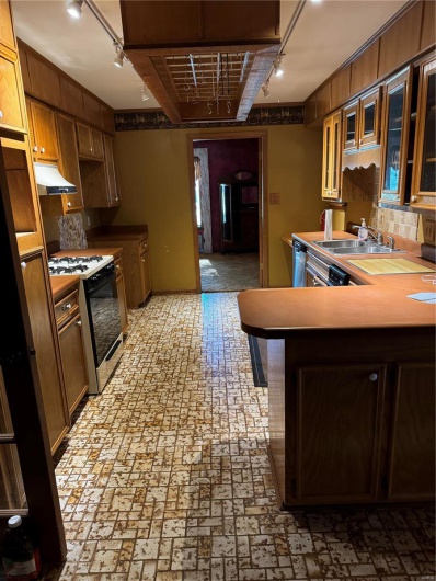 Kitchen featuring kitchen peninsula, range, dishwasher, sink, and ventilation hood