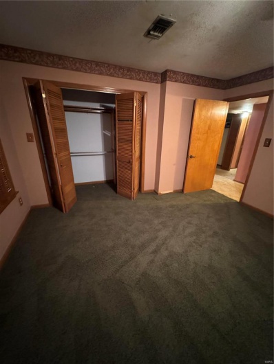 Carpeted bedroom featuring a closet and a textured ceiling