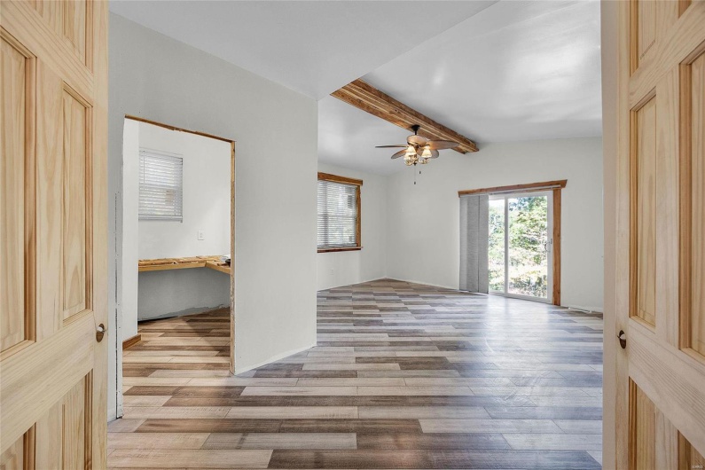 Primary bedroom with ceiling fan, beamed ceiling, and bamboo flooring
