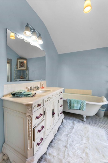 Bathroom with vanity, a bathing tub, and vaulted ceiling