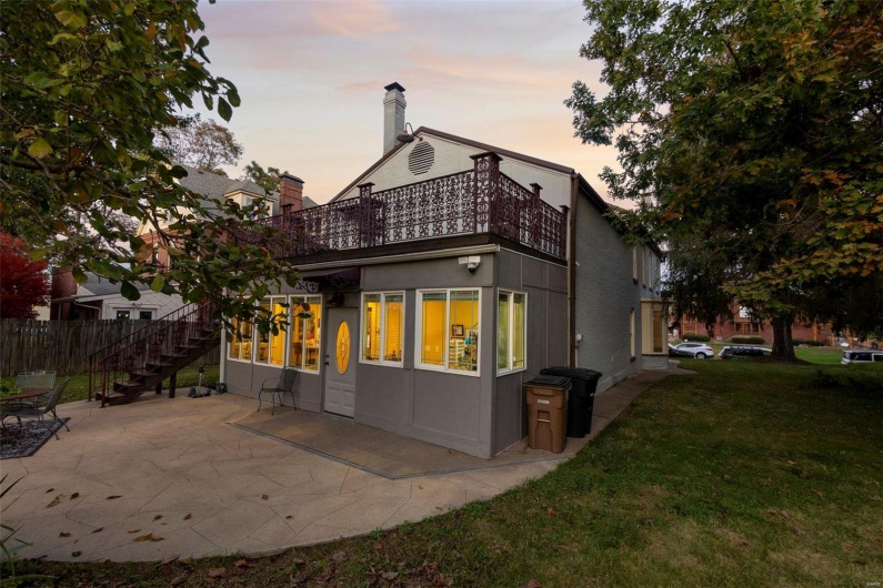 Back house at dusk with a patio area and a lawn