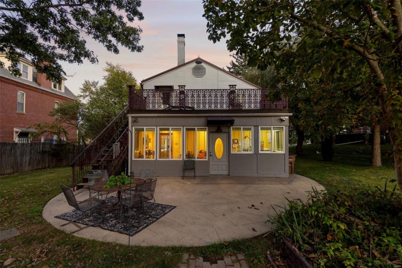 Back house at dusk with a patio area and a lawn