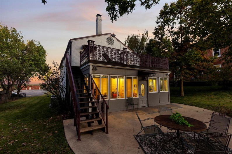 Back house at dusk with a patio area and a lawn