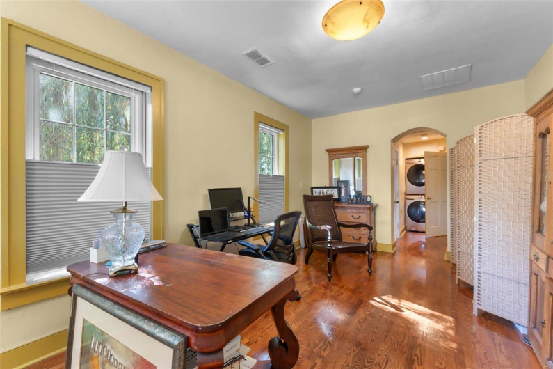 Office with stacked washing maching and dryer, dark hardwood / wood-style flooring, and plenty of natural light