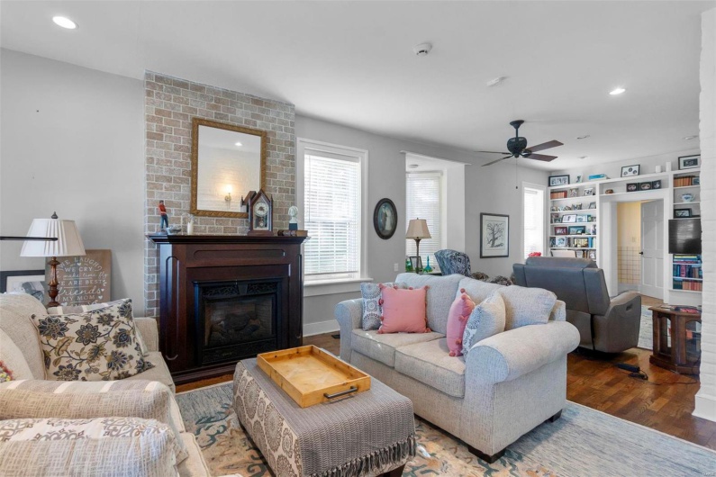 Living room featuring a brick fireplace, hardwood / wood-style flooring, and ceiling fan