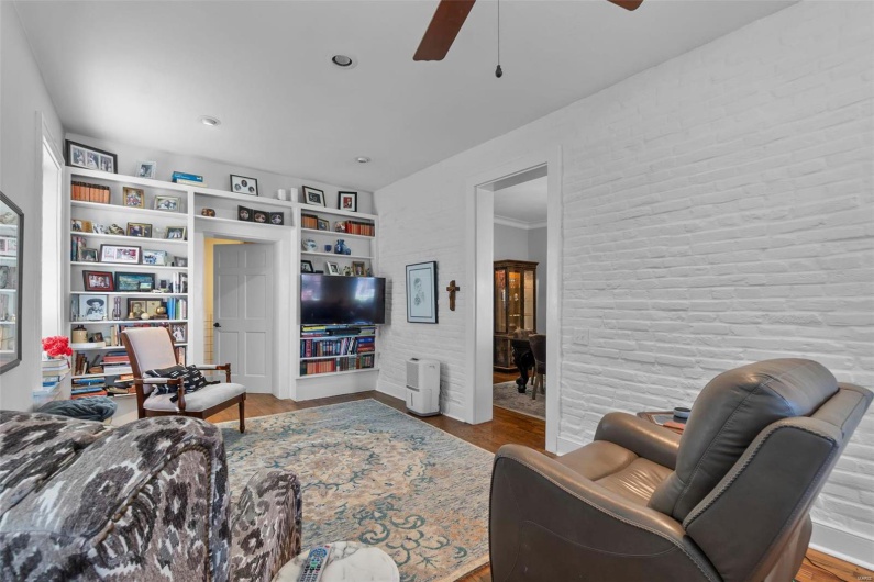 Living room featuring ceiling fan, wood-type flooring, and built in shelves