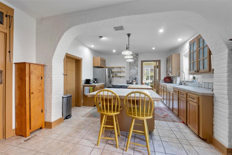 Kitchen featuring a kitchen island, a kitchen breakfast bar, sink, stainless steel fridge with ice dispenser, and decorative light fixtures