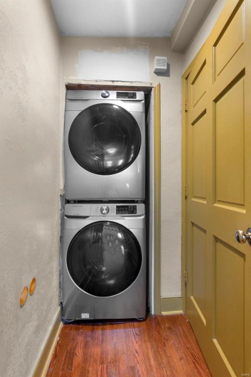 Washroom with stacked washer / dryer and dark hardwood / wood-style floors