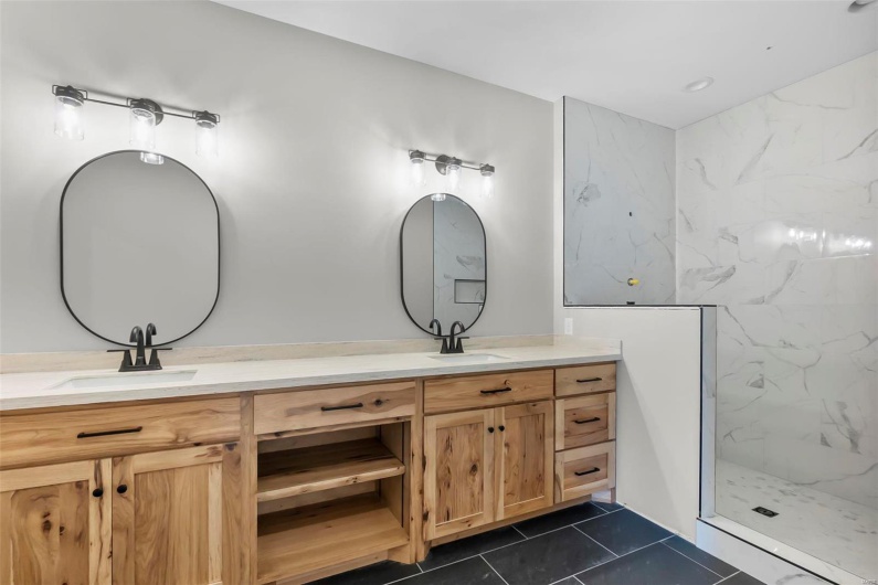 Bathroom with a tile shower, tile patterned floors, and vanity