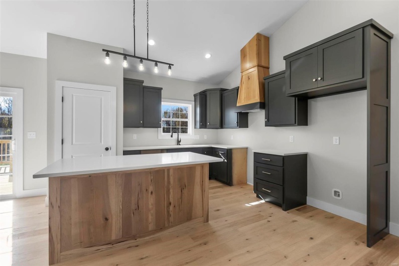 Kitchen with pendant lighting, lofted ceiling, a kitchen island, and light wood-type flooring