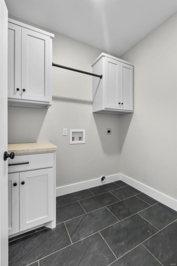 Laundry area featuring hookup for a washing machine, cabinets, dark tile patterned flooring, and hookup for an electric dryer