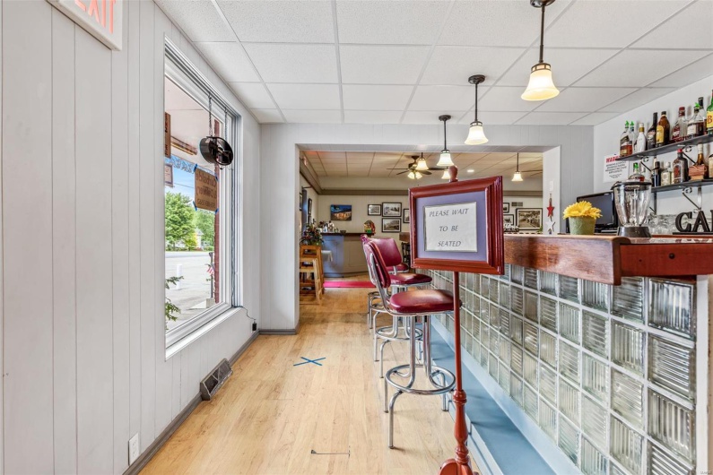 Bar featuring wood walls, a drop ceiling, light hardwood / wood-style floors, ceiling fan, and decorative light fixtures