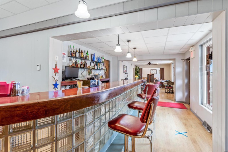 Bar featuring hardwood / wood-style floors, a paneled ceiling, and ceiling fan