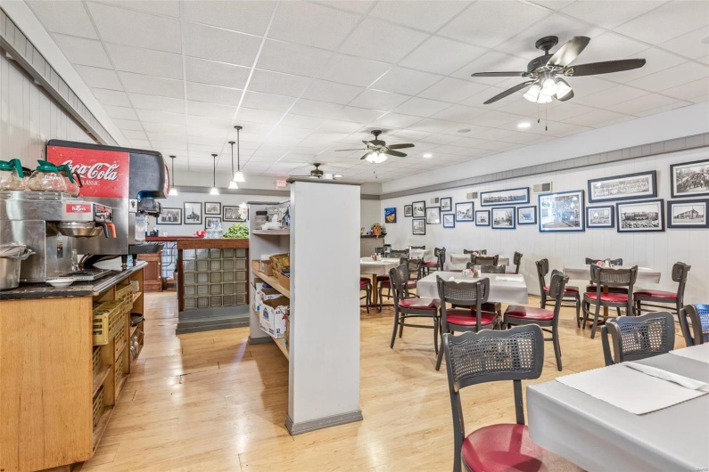Dining space with ceiling fan, a drop ceiling, and light wood-type flooring