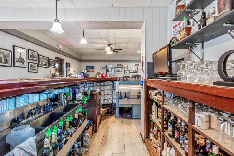 Miscellaneous room featuring light hardwood / wood-style floors, bar, and ceiling fan