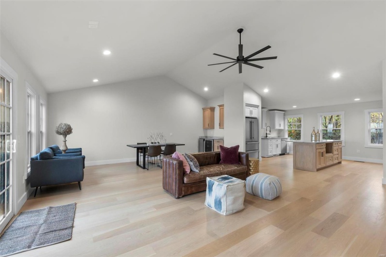 Living room with sink, vaulted ceiling, light hardwood / wood-style flooring, and ceiling fan