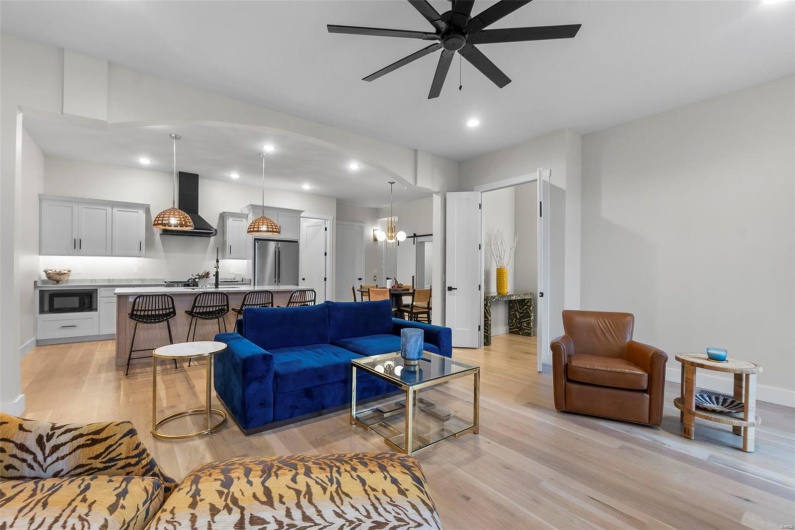 Living room featuring ceiling fan with notable chandelier and light wood-type flooring