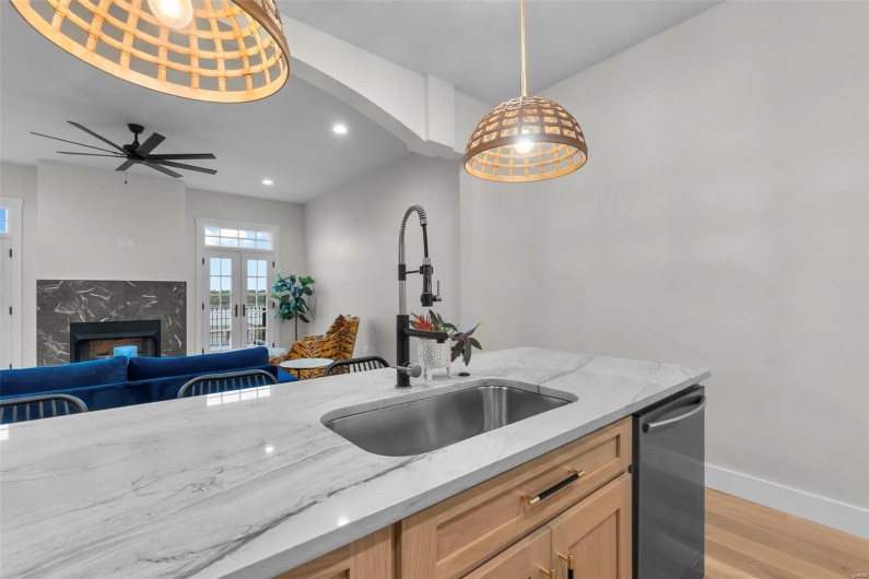 Kitchen featuring light hardwood / wood-style floors, decorative light fixtures, sink, and light stone counters