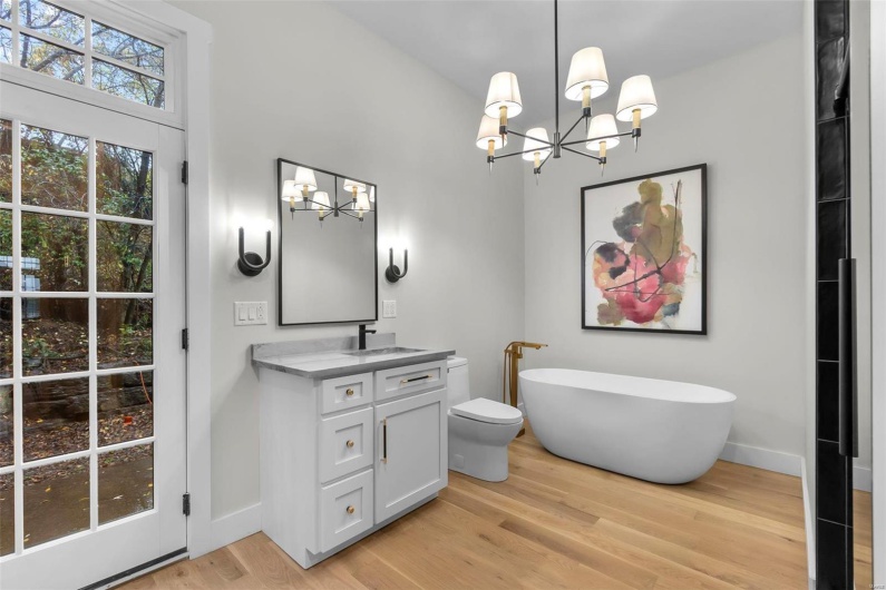 Bathroom with hardwood / wood-style floors, a bathtub, a chandelier, toilet, and vanity