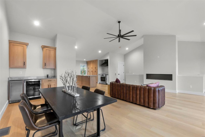 Dining room with lofted ceiling, ceiling fan, light wood-type flooring, and beverage cooler