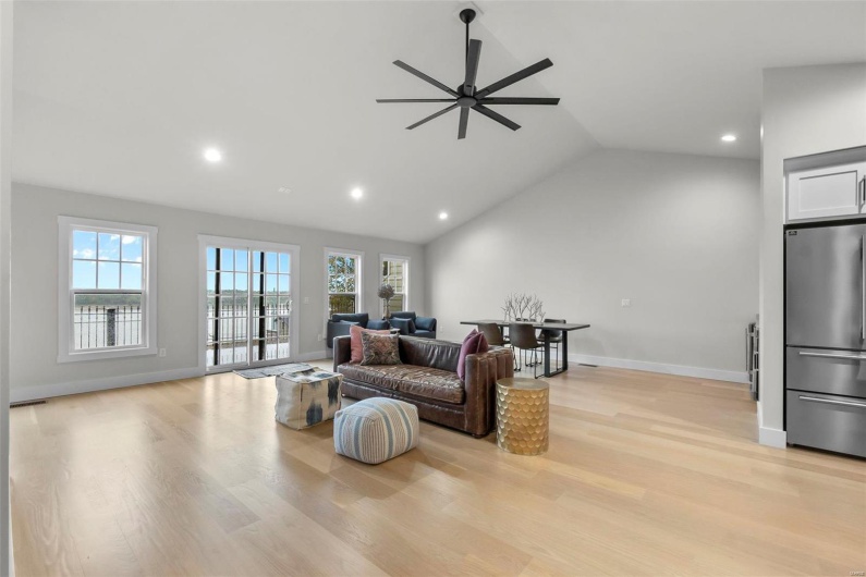 Living room featuring light hardwood / wood-style floors, vaulted ceiling, and ceiling fan