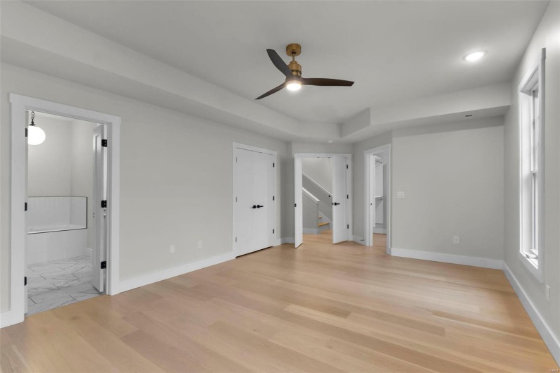 Unfurnished bedroom featuring ensuite bathroom, light hardwood / wood-style floors, and ceiling fan