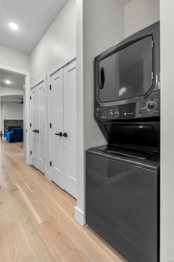 Laundry area featuring ceiling fan, light hardwood / wood-style floors, and stacked washing maching and dryer