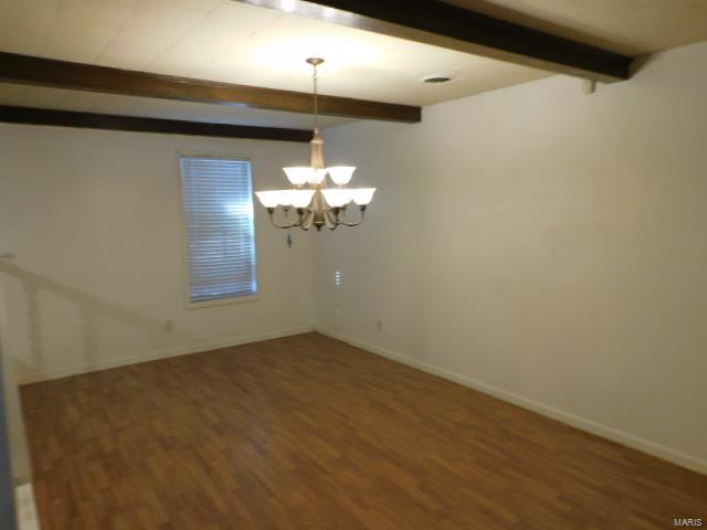 Spare room with an inviting chandelier, beam ceiling, and dark hardwood / wood-style flooring