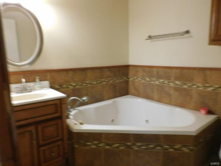 Bathroom featuring vanity and tiled tub