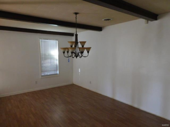 Unfurnished dining area with beamed ceiling, dark hardwood / wood-style flooring, and an inviting chandelier