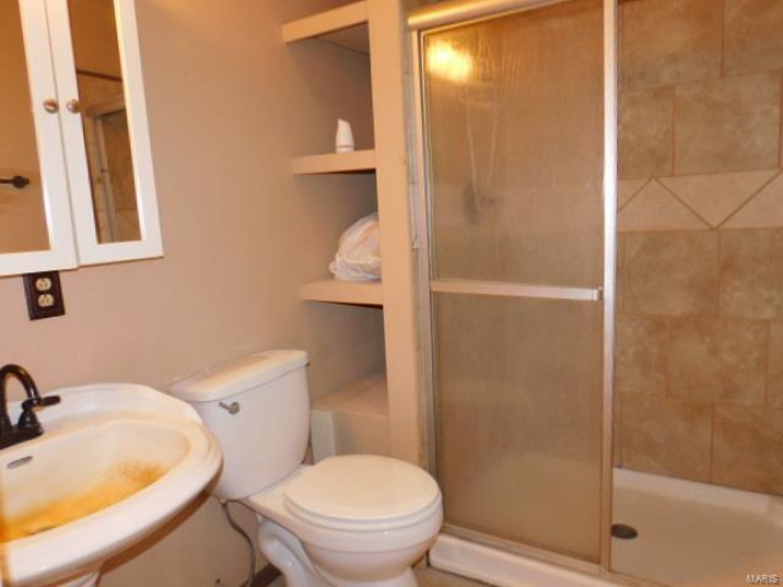 Bathroom featuring sink, toilet, and an enclosed shower