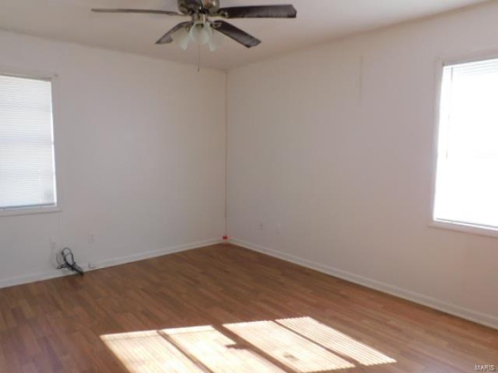 Empty room featuring ceiling fan, dark hardwood / wood-style flooring, and plenty of natural light