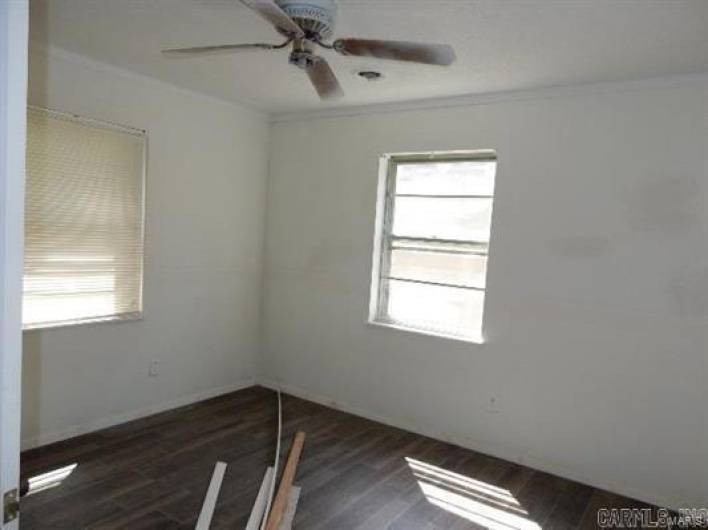 Spare room with crown molding, dark hardwood / wood-style floors, and ceiling fan