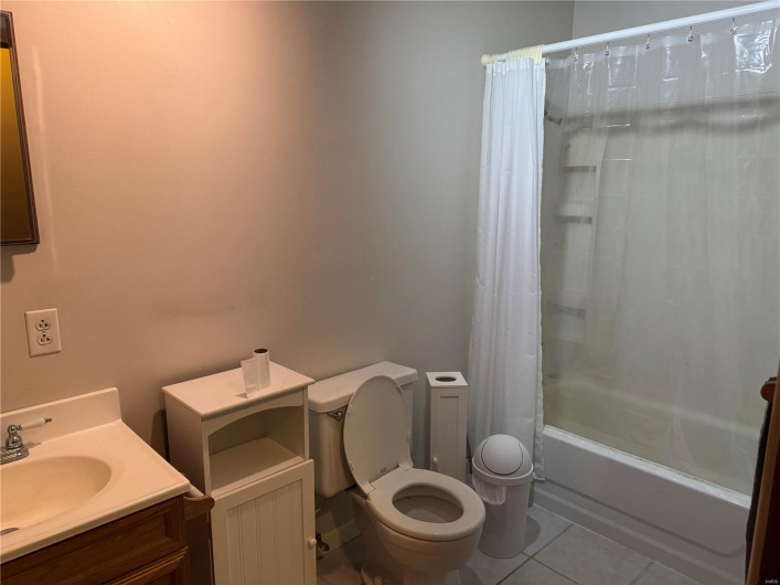 Full bathroom with shower / tub combo with curtain, vanity, toilet, and tile patterned flooring