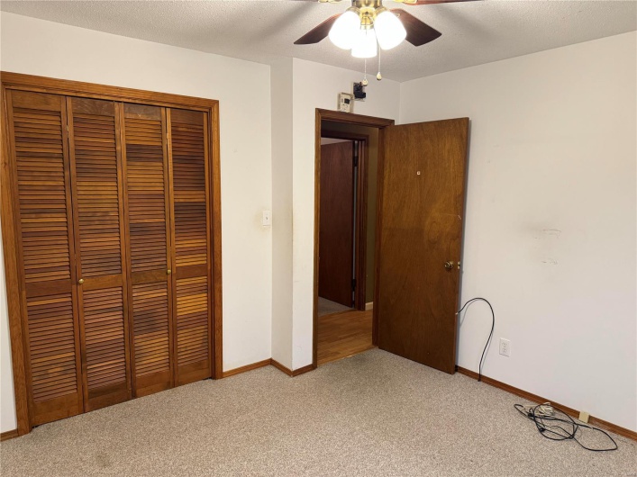 Unfurnished bedroom with ceiling fan, a textured ceiling, a closet, and light colored carpet