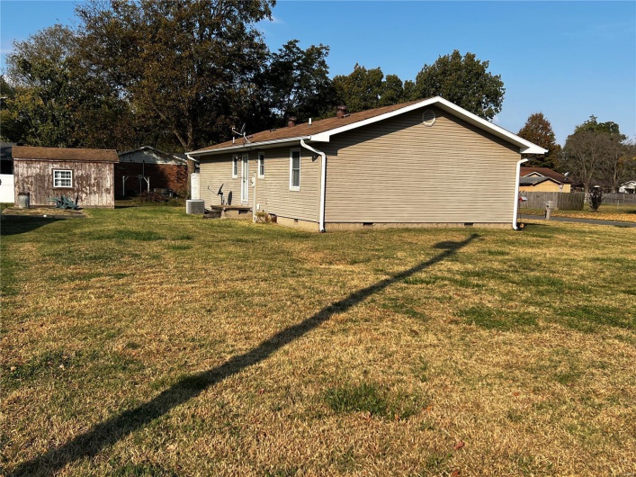 View of home's exterior with a storage unit, a lawn, and central AC