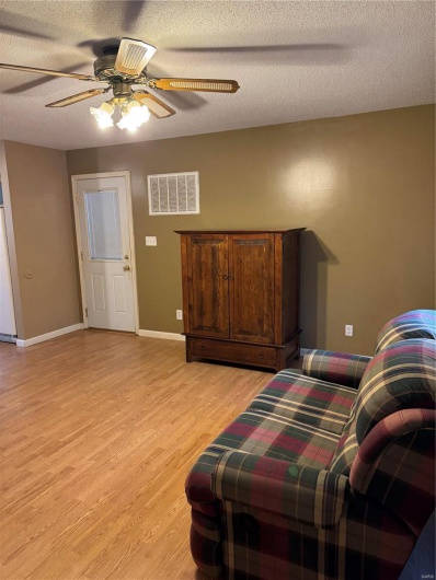 Sitting room with ceiling fan, a textured ceiling, and light wood-type flooring