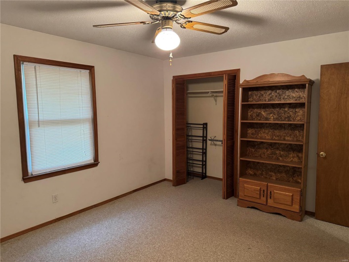 Unfurnished bedroom featuring a closet, a textured ceiling, light carpet, and ceiling fan