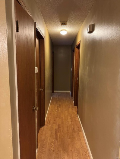 Corridor featuring light wood-type flooring and a textured ceiling