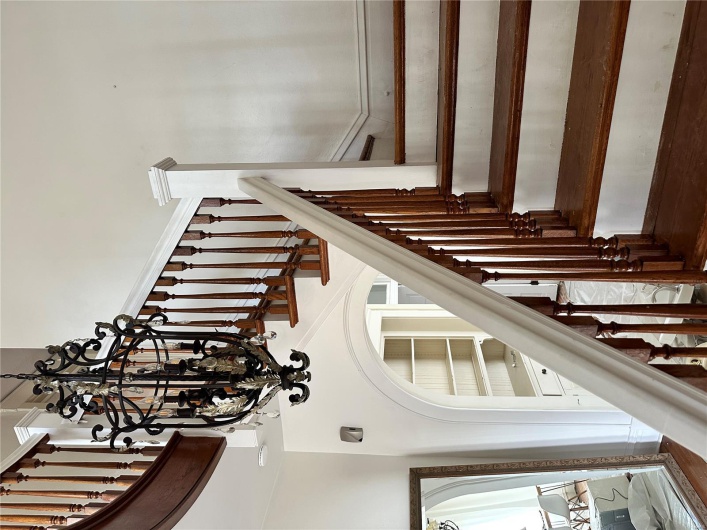 Stairs with a towering ceiling, a chandelier, and built in shelves