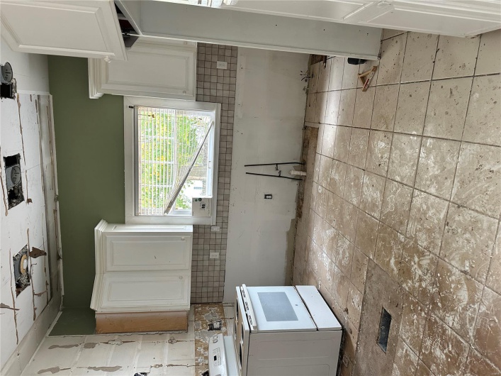 Kitchen featuring decorative backsplash, white cabinetry, visible vents, and stove