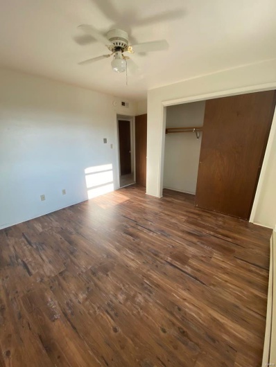 Unfurnished bedroom featuring a closet, dark hardwood / wood-style floors, and ceiling fan