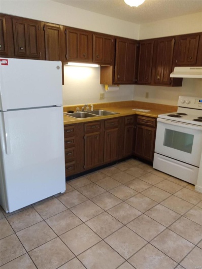 Kitchen with a textured ceiling, light tile patterned flooring, white appliances, and sink