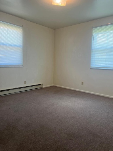 Unfurnished room with carpet flooring, plenty of natural light, and baseboard heating