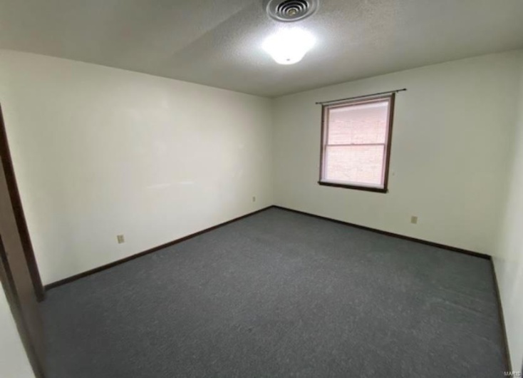 Carpeted empty room featuring a textured ceiling
