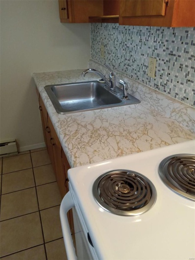 Kitchen featuring decorative backsplash, sink, light tile patterned flooring, and white range