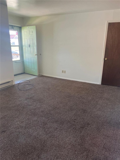 Spare room with carpet flooring and a baseboard heating unit