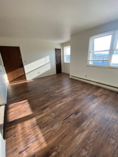 Unfurnished living room with dark hardwood / wood-style flooring and a baseboard heating unit