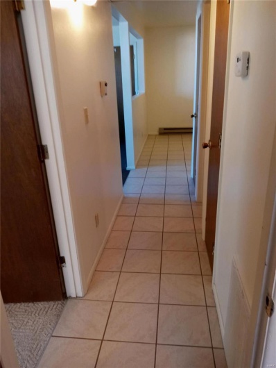 Corridor featuring light tile patterned floors and a baseboard heating unit